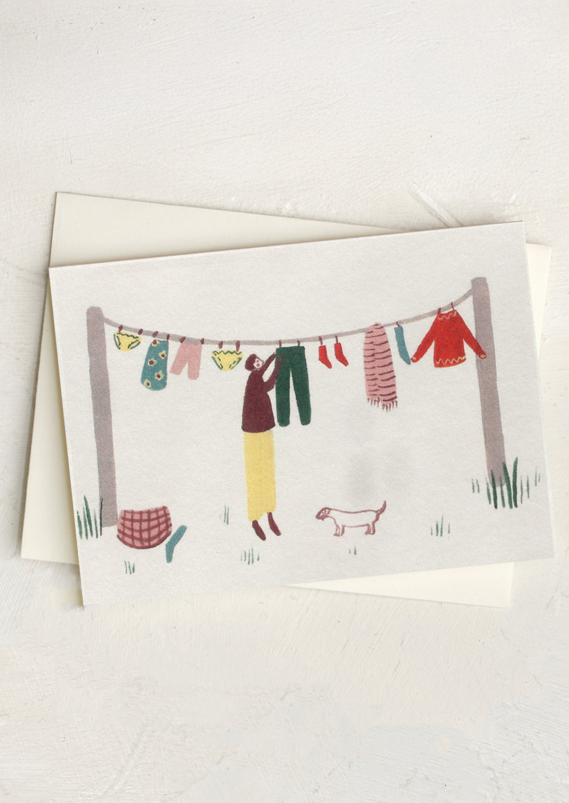 A small greeting card with illustration of person hanging things on a clothesline.