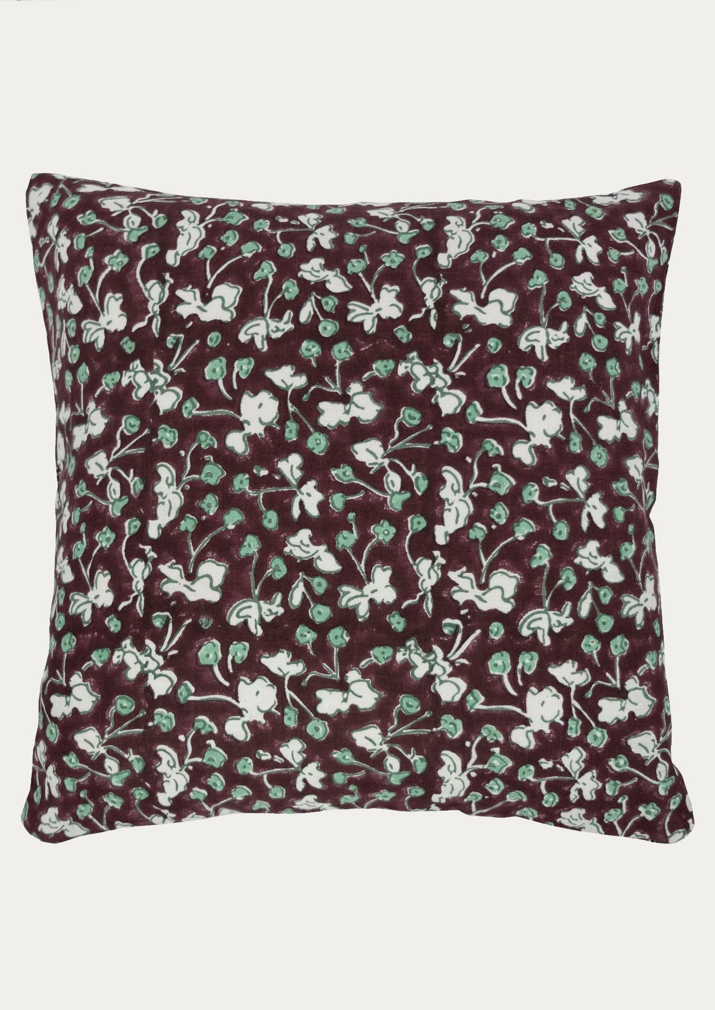 A throw pillow in dark chocolate color with green and white floral botanical print.