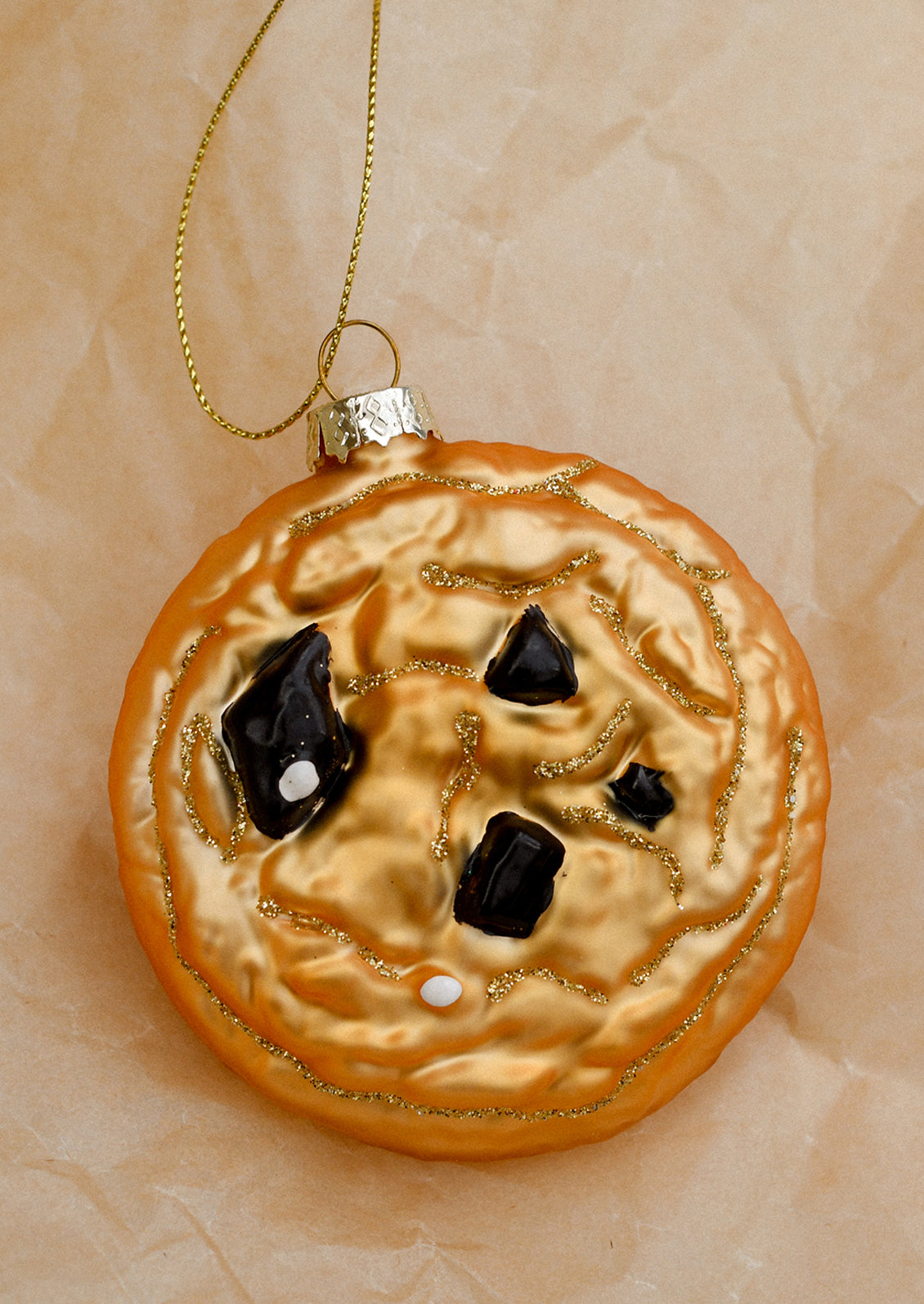 A glass ornament resembling a chocolate chip cookie.