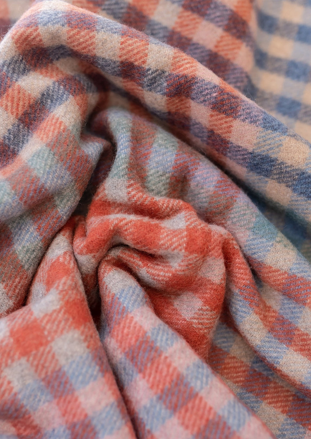 3: A gingham check patterned wool blanket in shades of red and cornflower blue.