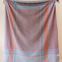 1: A gingham check patterned wool blanket in shades of red and cornflower blue.