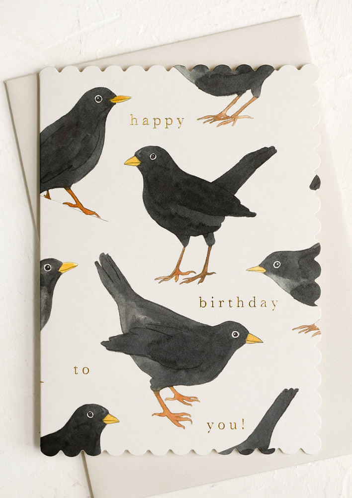 A greeting card with scalloped edges and blackbird print reading "Happy birthday to you".