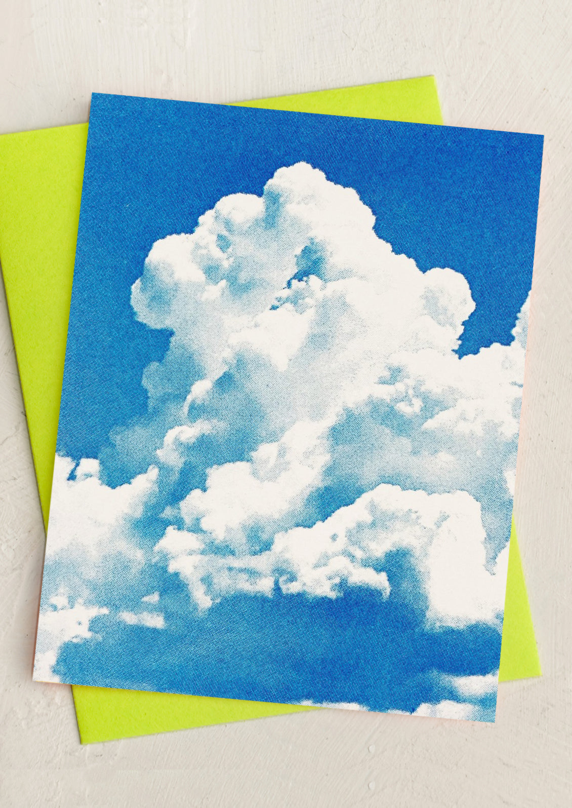 Card with a cloud design on a blue background, placed on a green envelope.