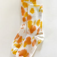 Daisy: A pair of tie dye socks in yellow and orange color.