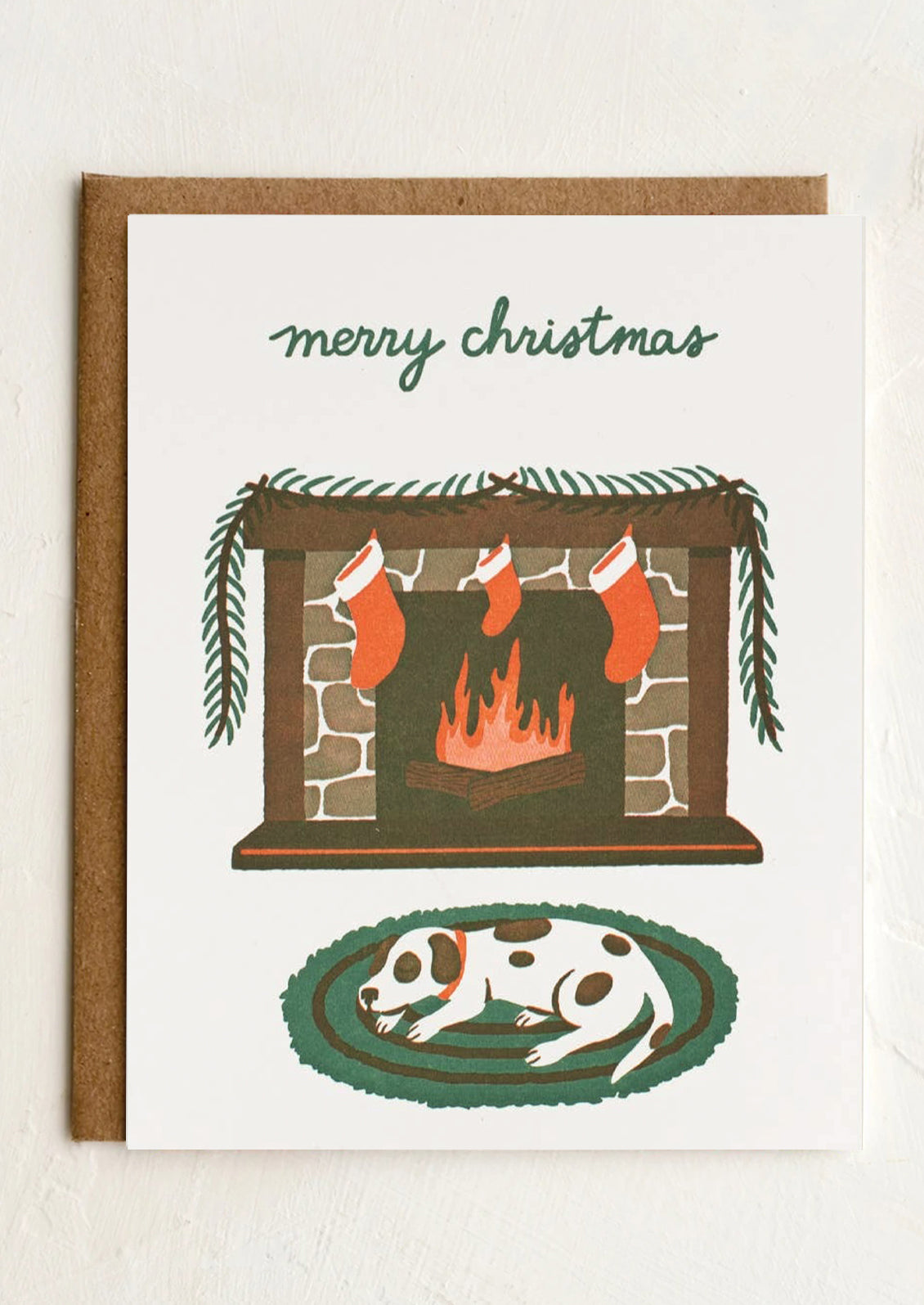 Christmas card with a fireplace, stockings, and a dog on a rug.