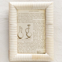 1: An ivory picture frame made of bone with puffy, ribbed border.