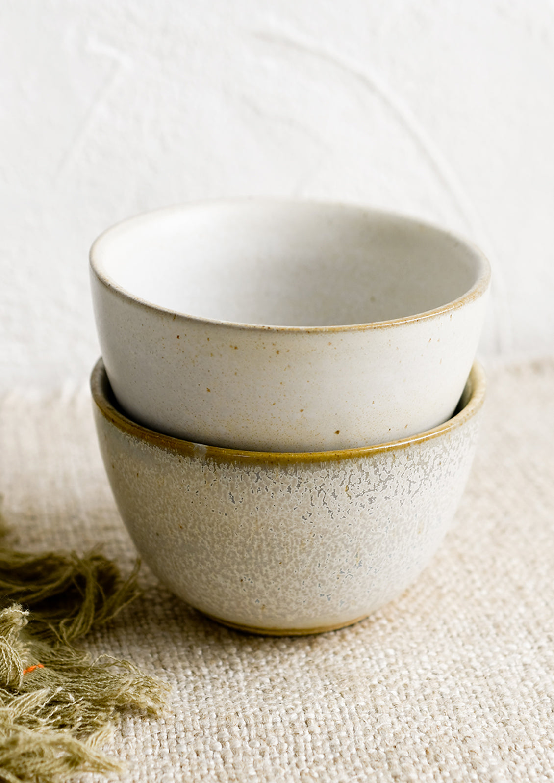 Two small ceramic bowls in natural speckle glazes.