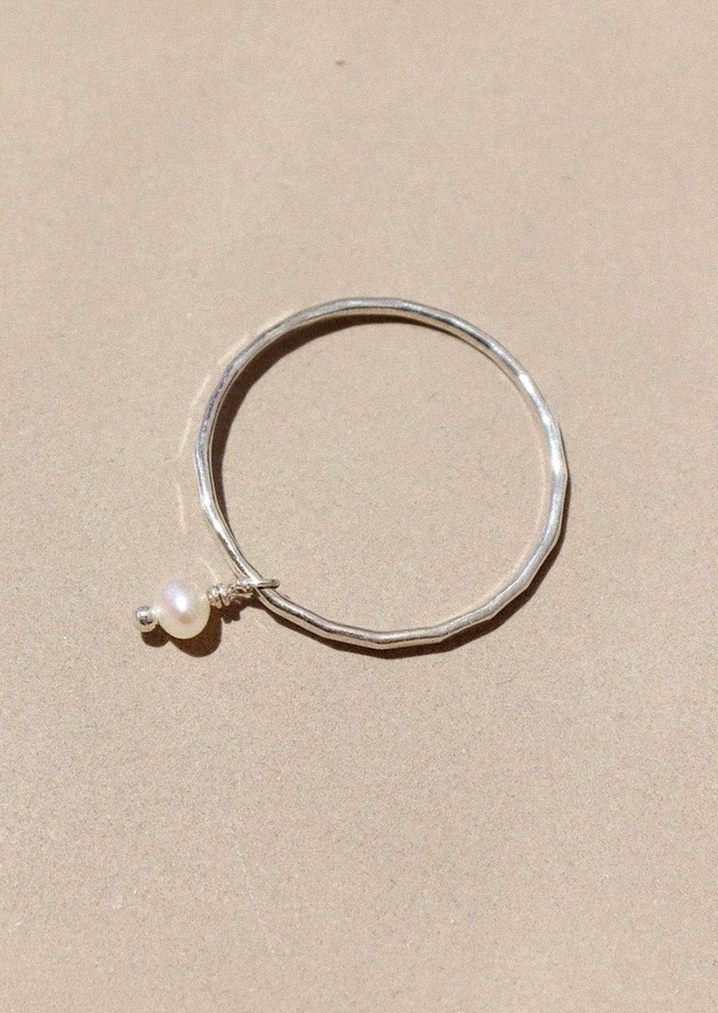 A sterling silver ring with dangling pearl bead.