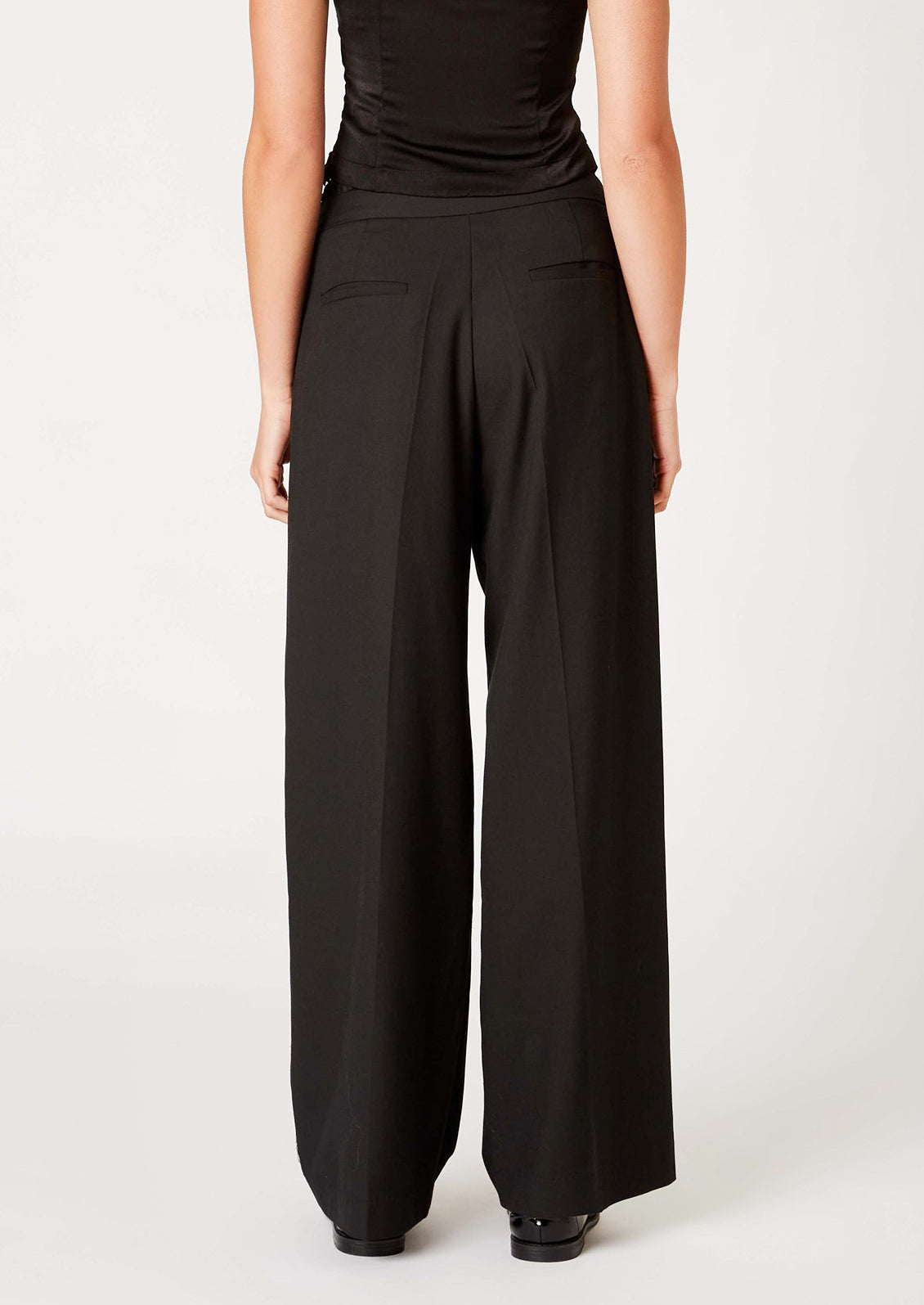 A woman wearing a pair of pants in black with ruched waistband detailing.