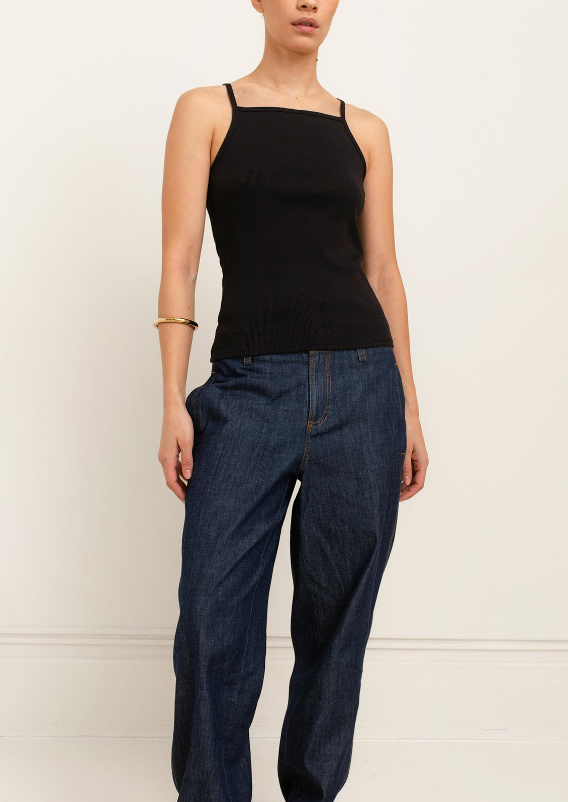 A person wearing a square neck racerback tank top in black.