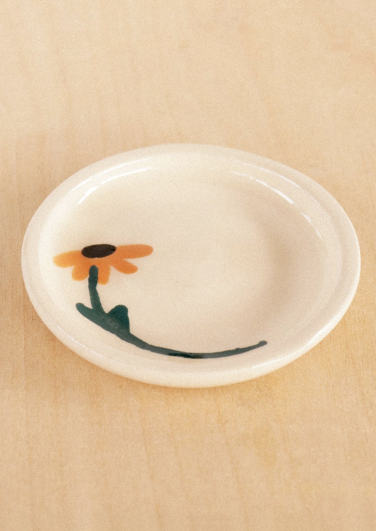 A round ceramic trinket dish in white with hand painted sunflower motif.