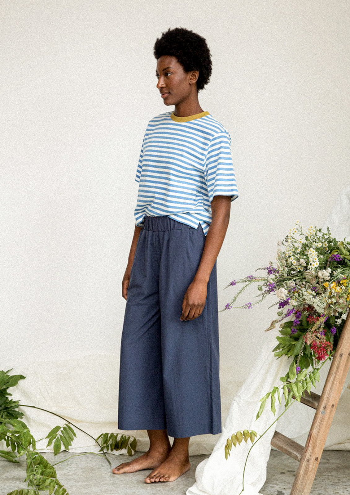 A woman wearing a blue and white striped tee with olive green collar.
