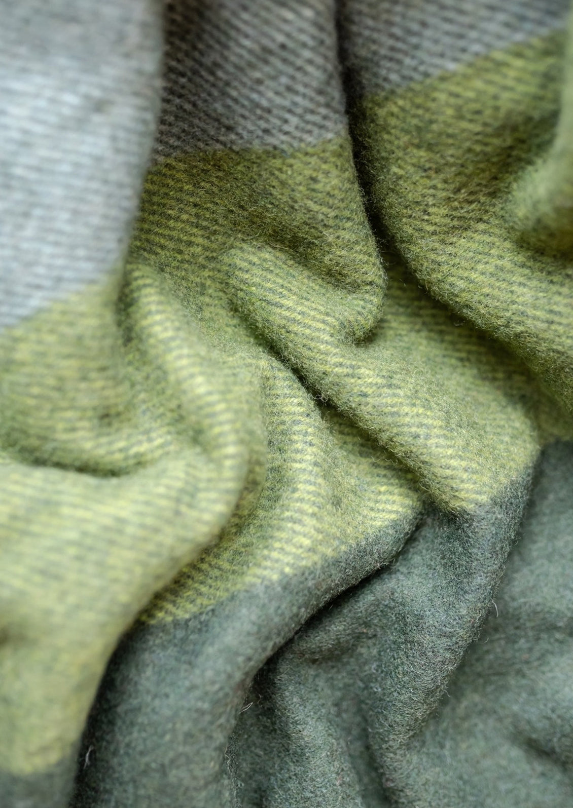 A recycled wool throw in olive green and beige check pattern.