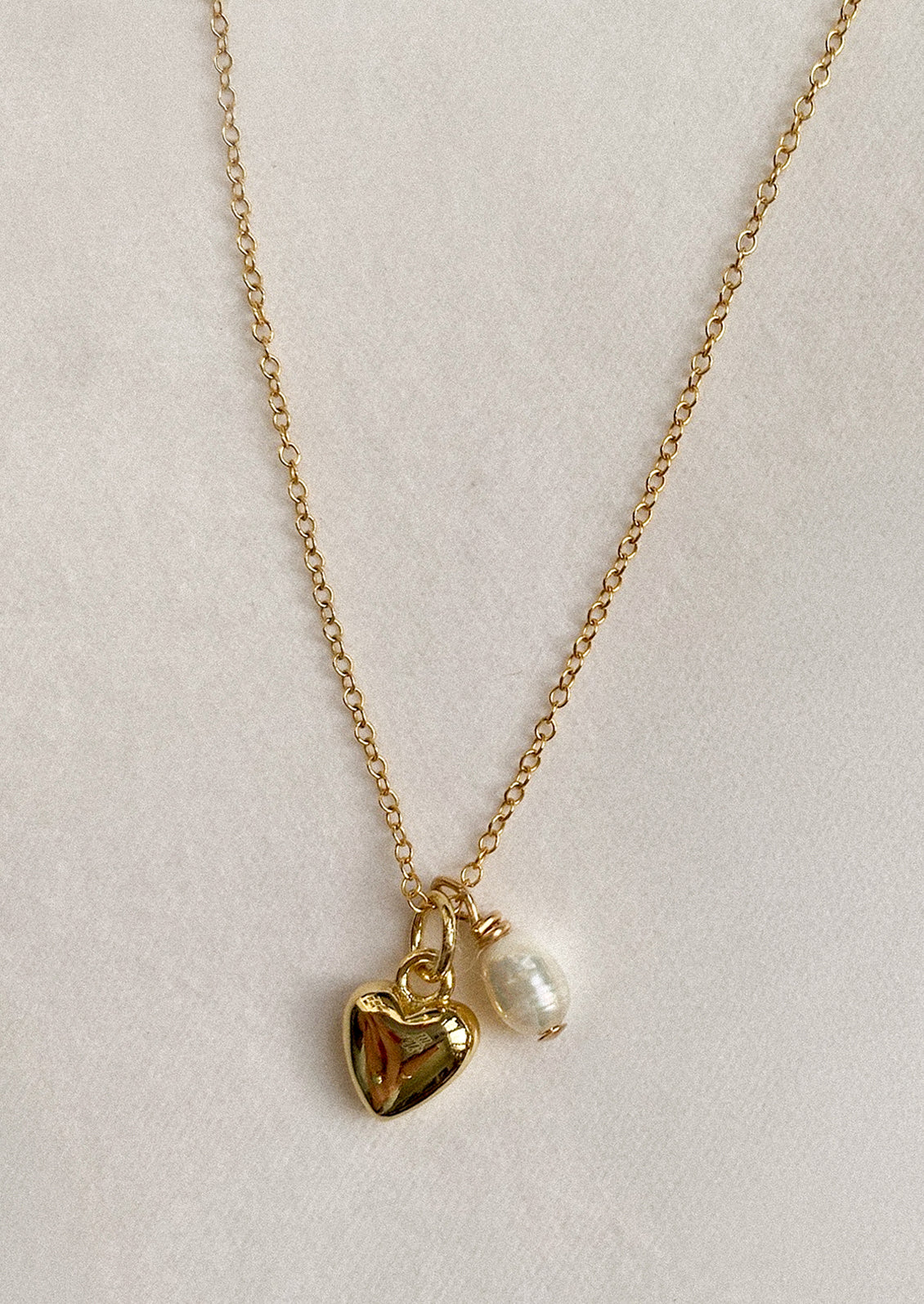 Gold necklace with a heart charm and pearl pendant.