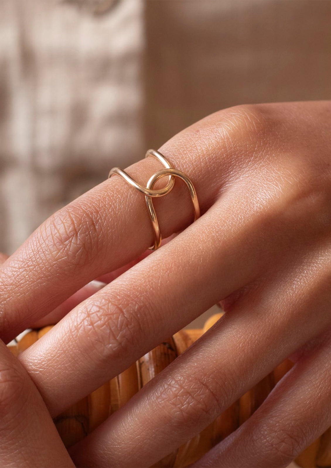 Close-up of a hand wearing a gold ring with a blurred background