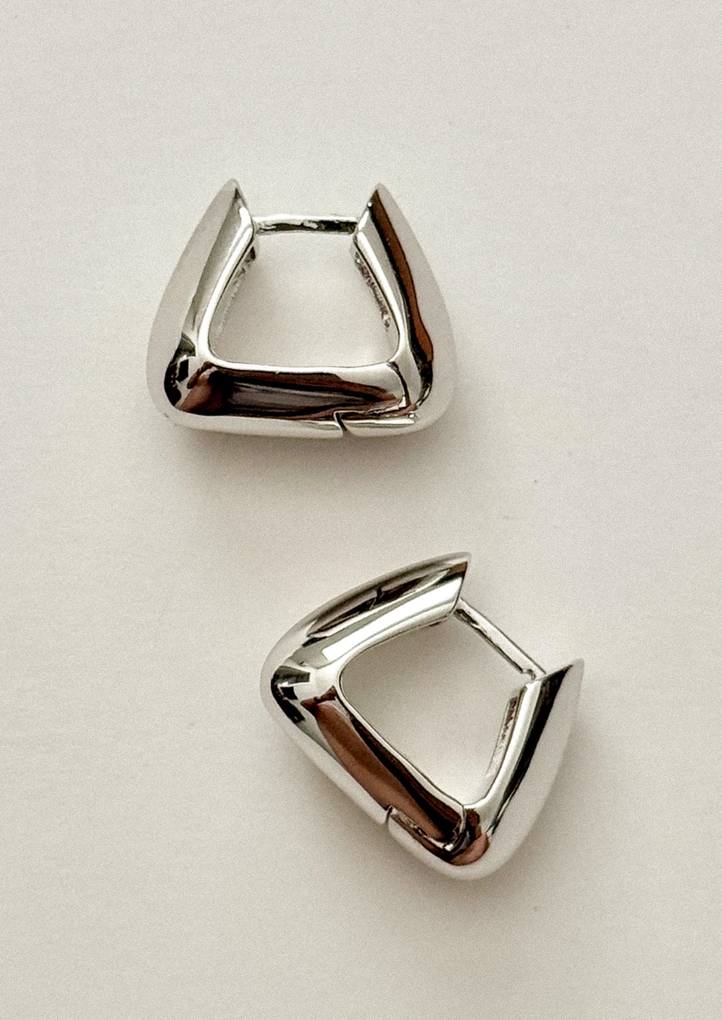 Pair of silver earring studs on a light beige background