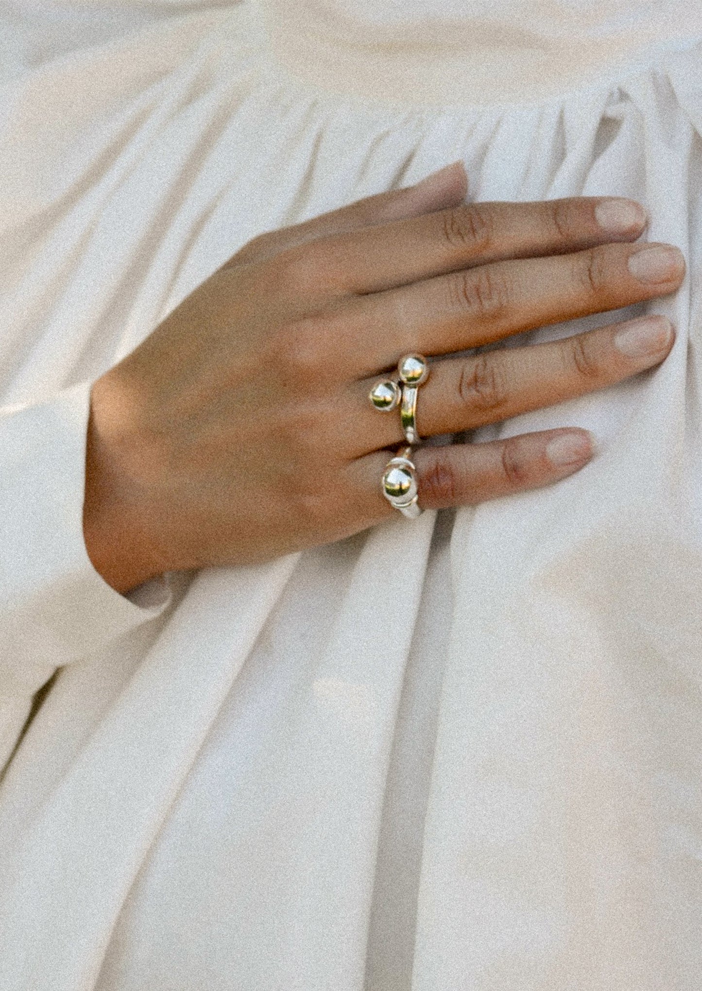 Hand wearing a gold ring on a light fabric background