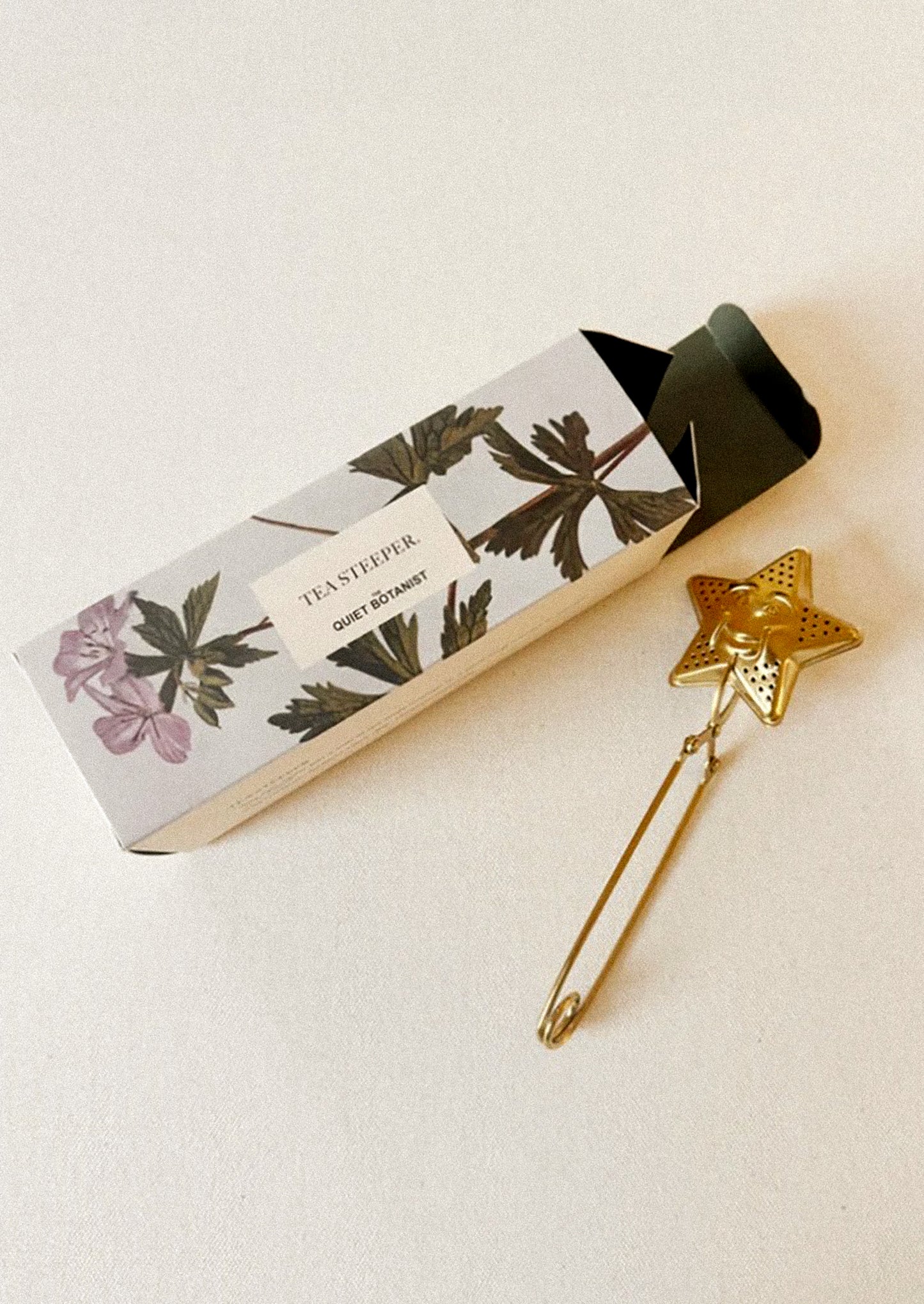 A brass tea steeper with star shaped end with smiling face.