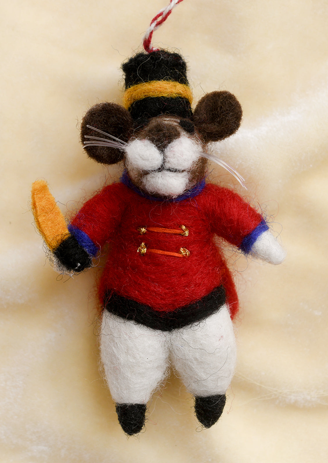 A felted wool ornament of mouse in drum major costume.