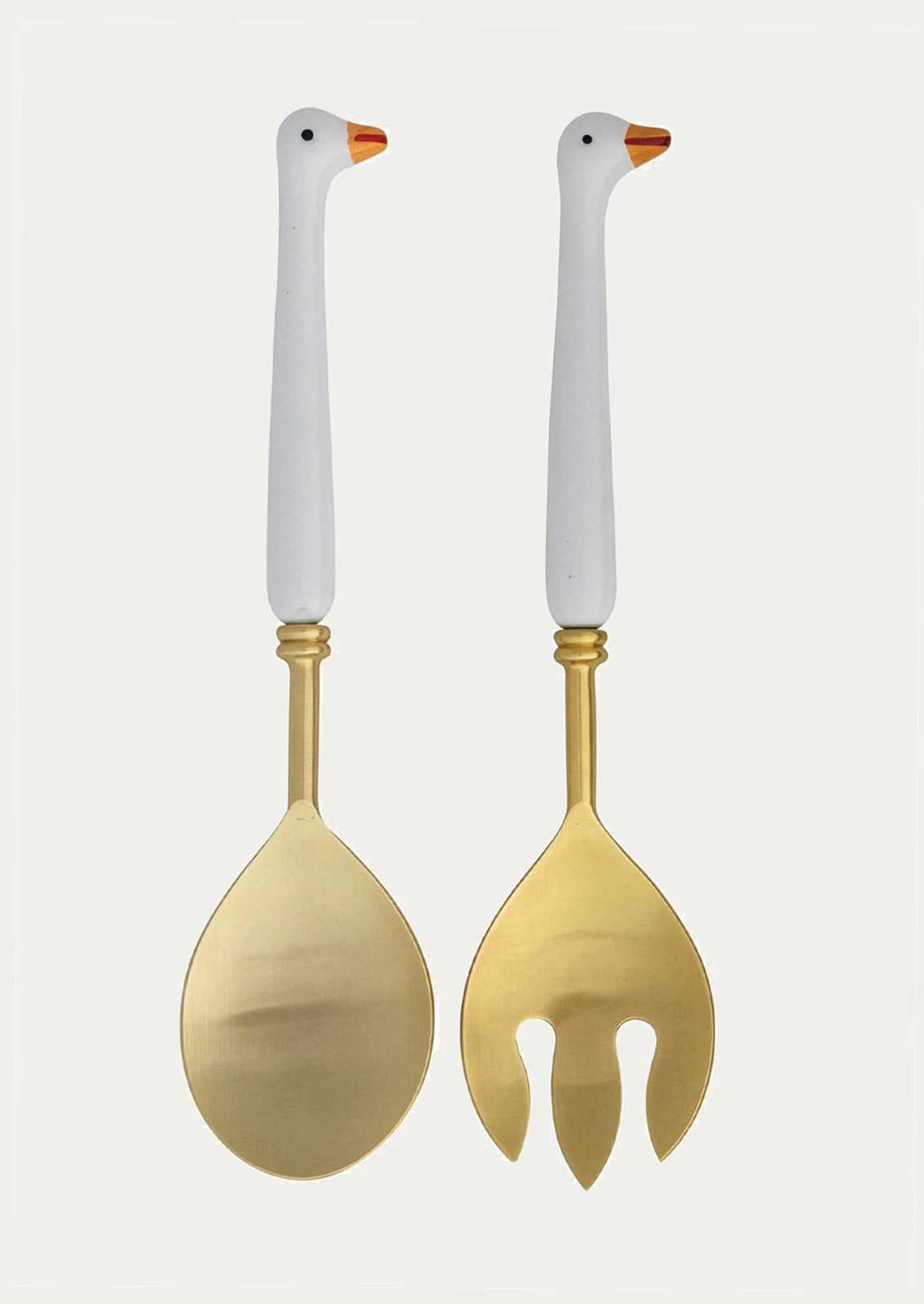 Two gold utensils with handles shaped like geese on a white background