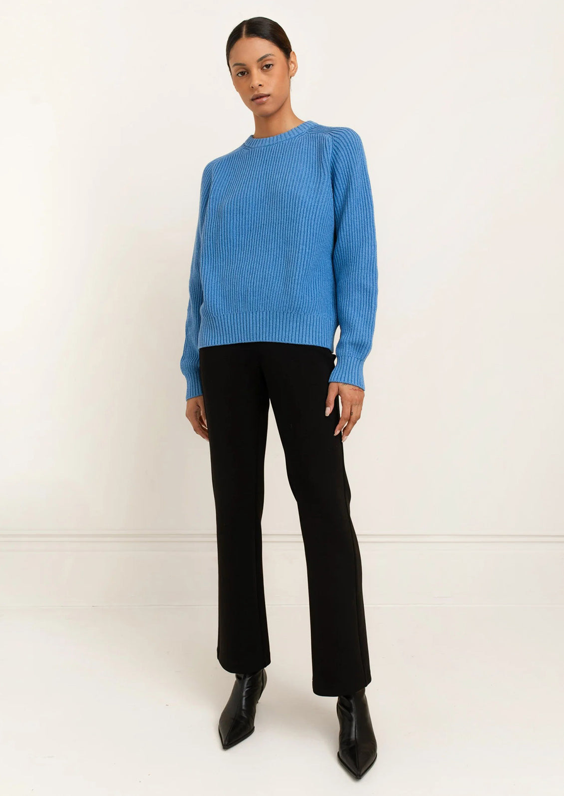 A woman wearing a rib knit sweater in blue.