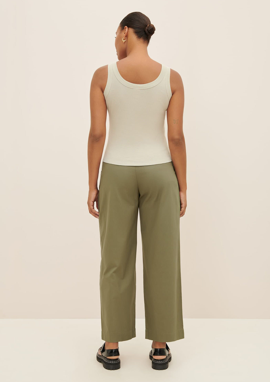 A woman wearing a scoop neck tank top in pale grey-green color.