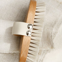 2: An oval shaped wood and bristle bath brush with elastic hand strap.