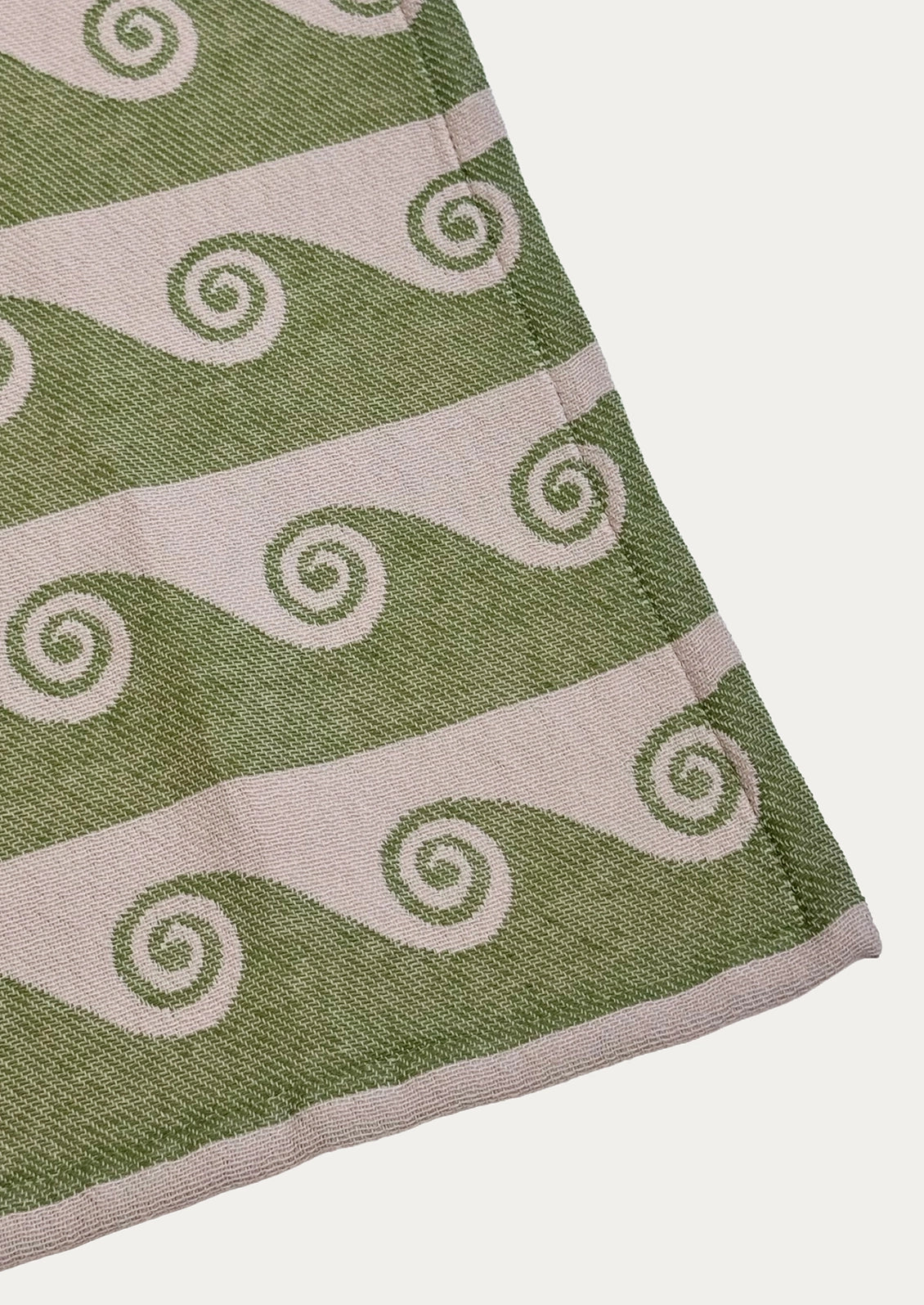 A jacquard weave tea towel with wave pattern in pink and green.