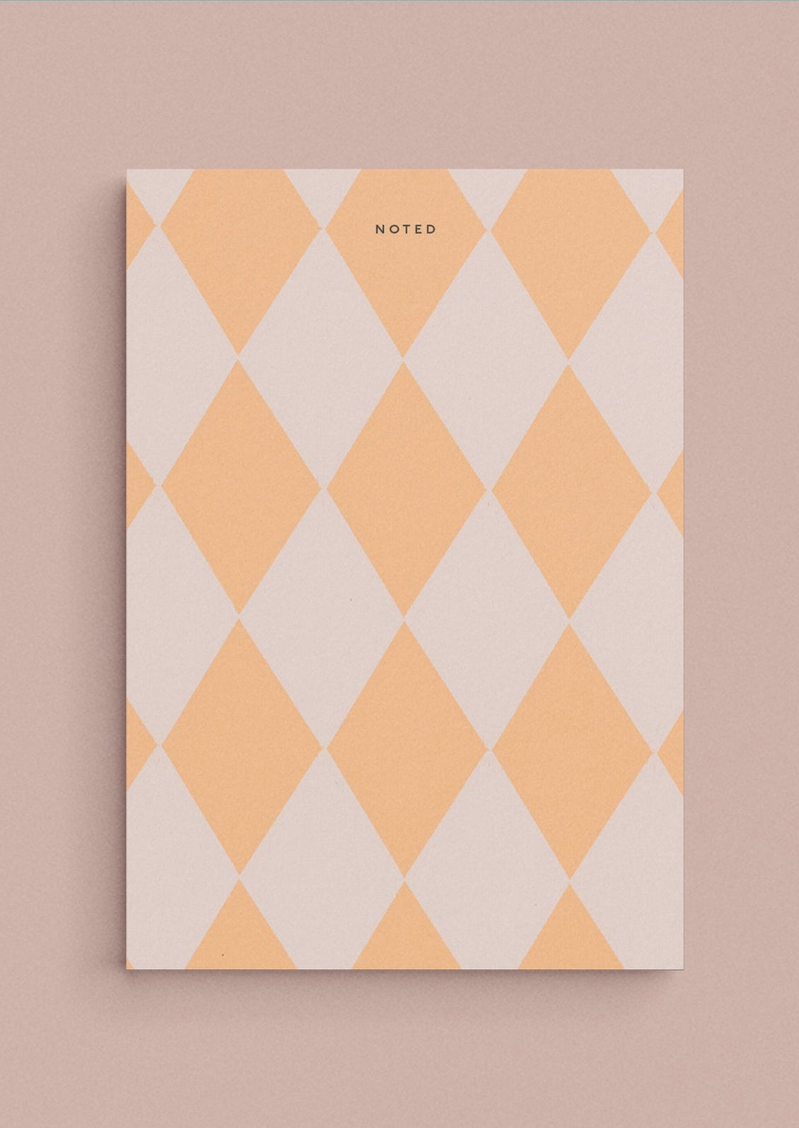 A diamond print notepad in peach and blush reading "NOTED" at the top.