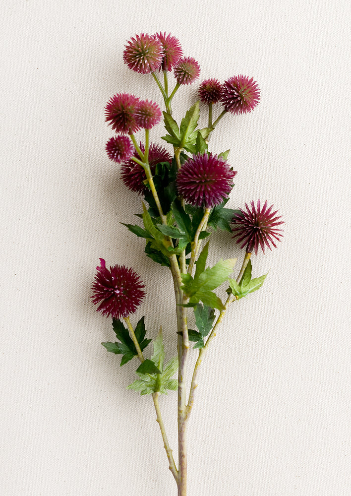 1: A faux spray of globe thistle flower in plum color.