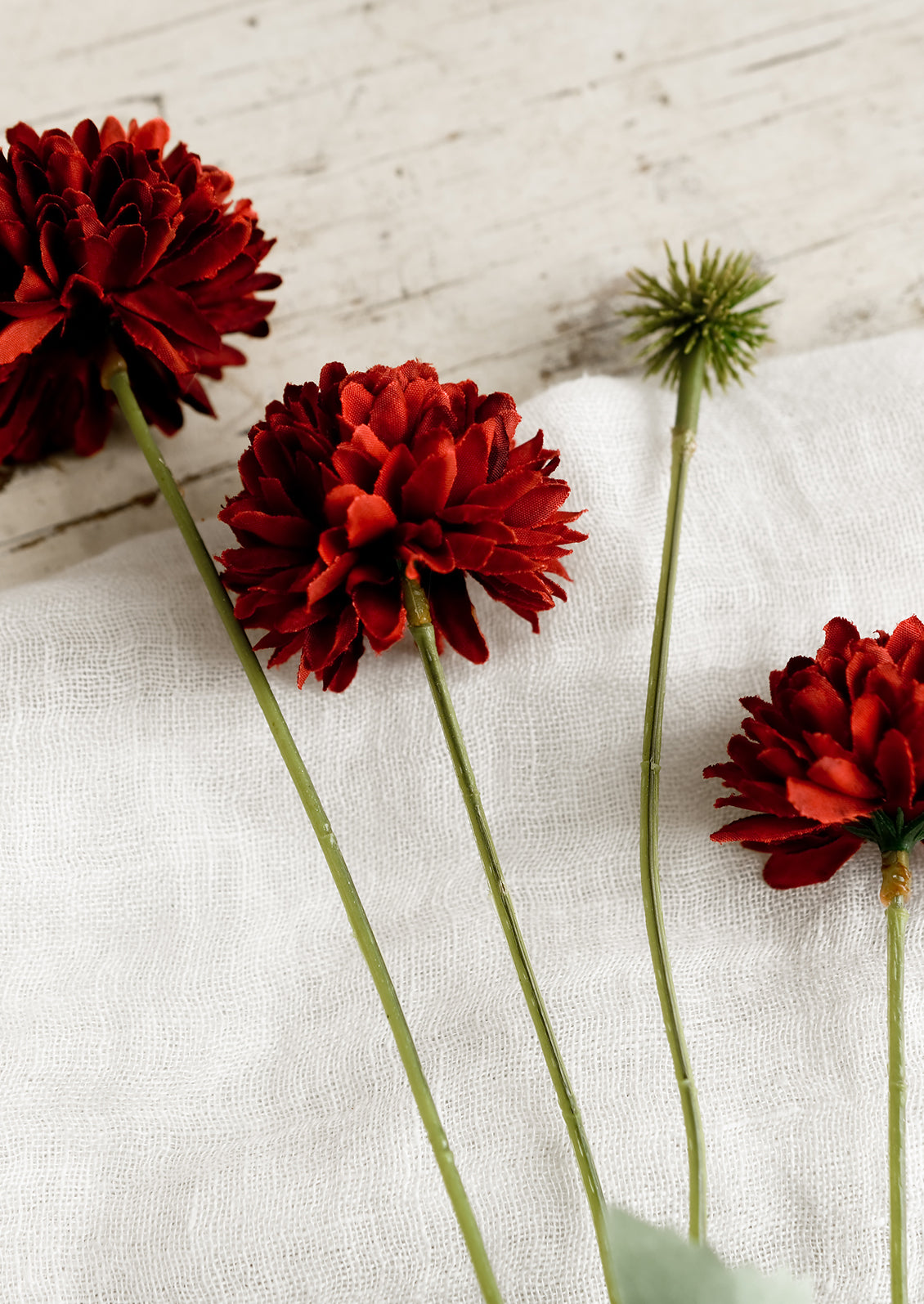 An artificial flower spray in the style of a red mum.