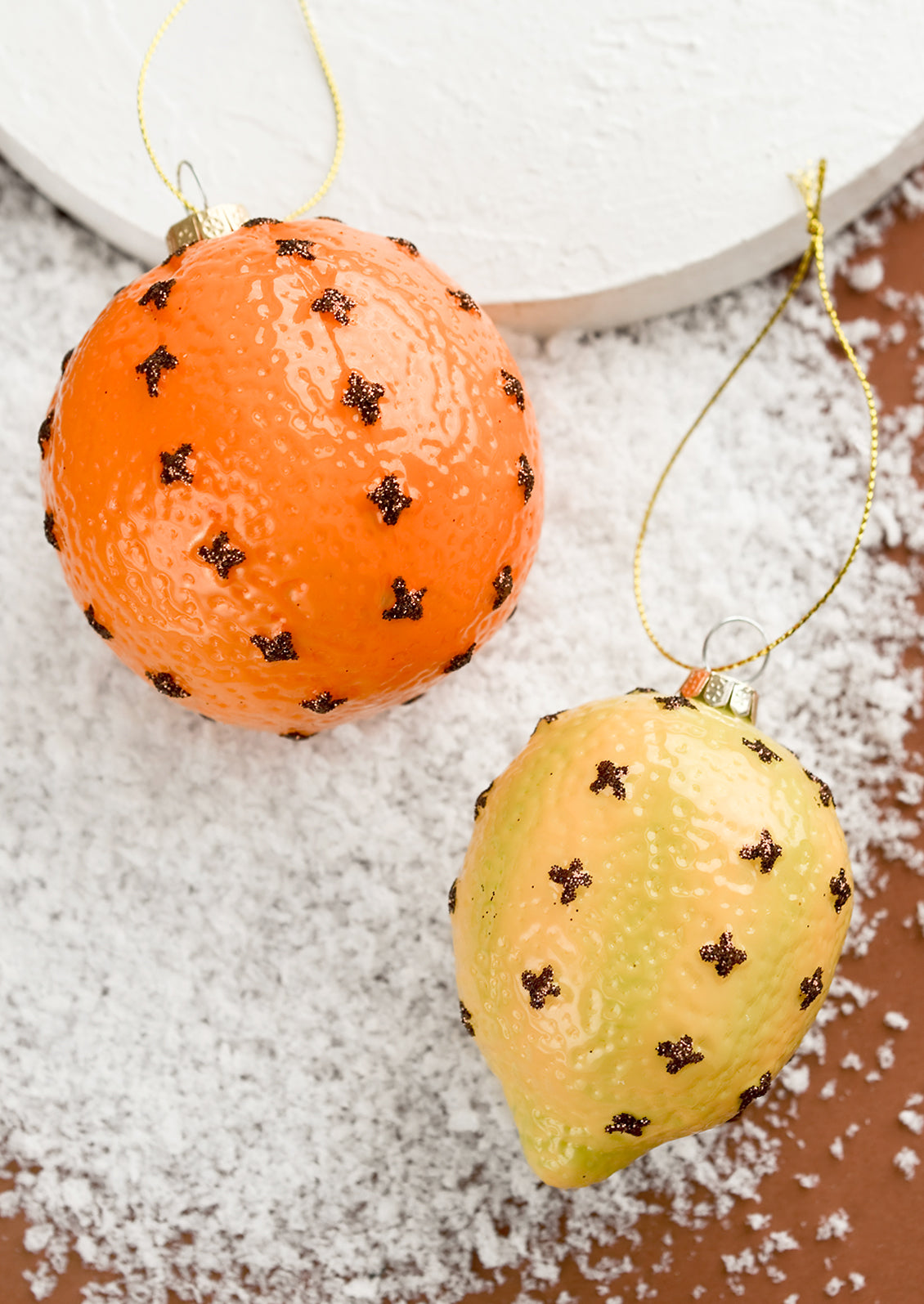 Glass ornaments of clove spiked lemon and orange.