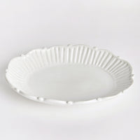 2: An oval shaped tray with ruffled and pleated border with ball detail around edges.