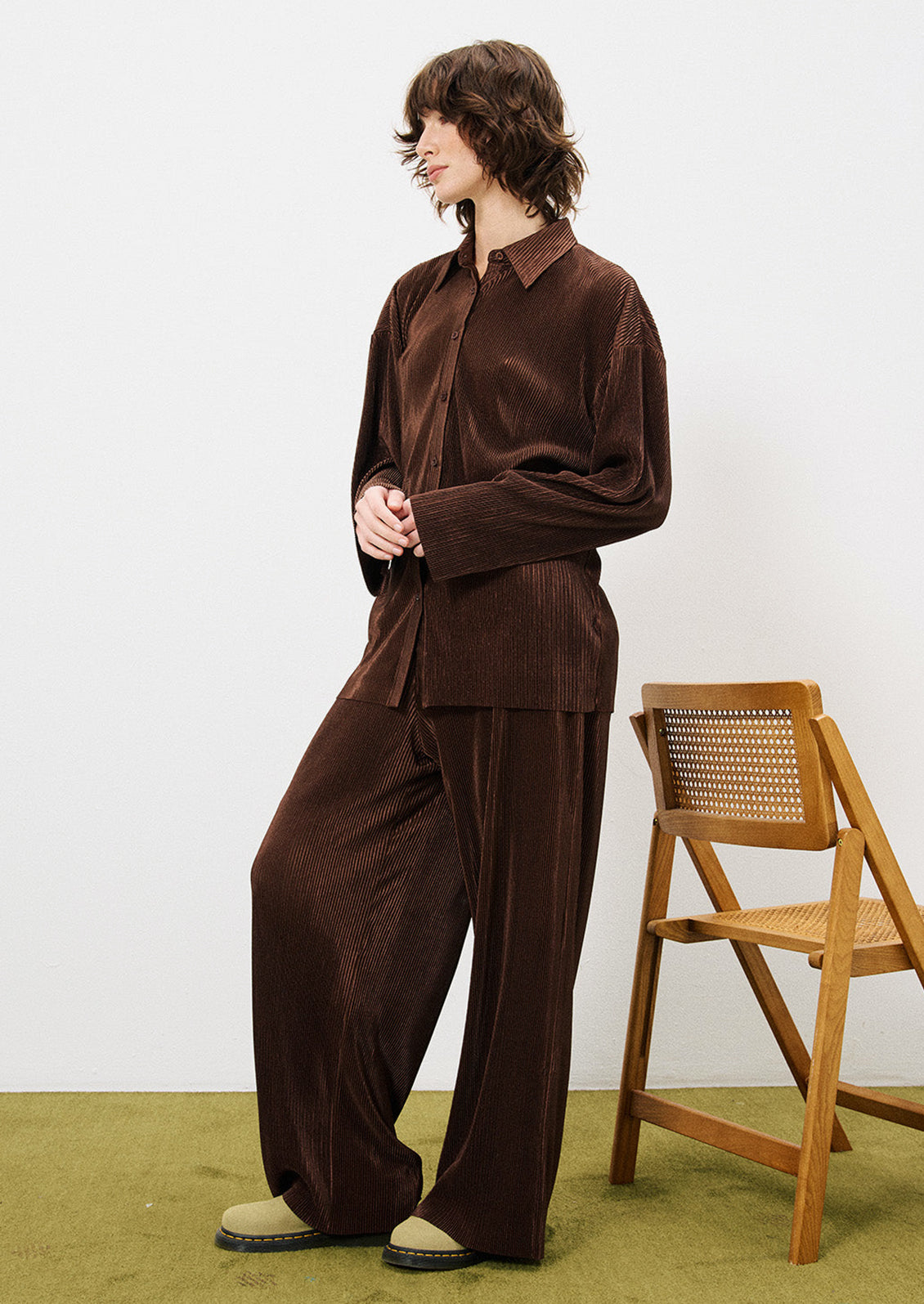 A woman wearing a pair of brown mini pleat pants.