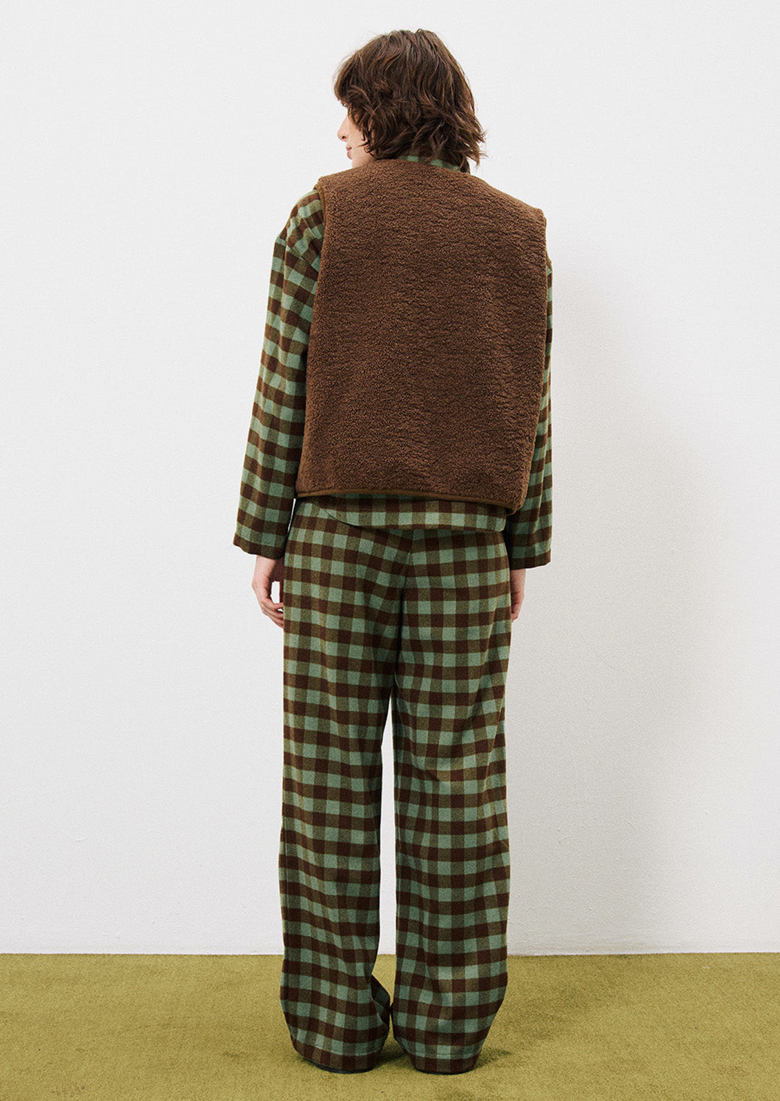 A person wearing a pair of pants in green and brown gingham pattern.
