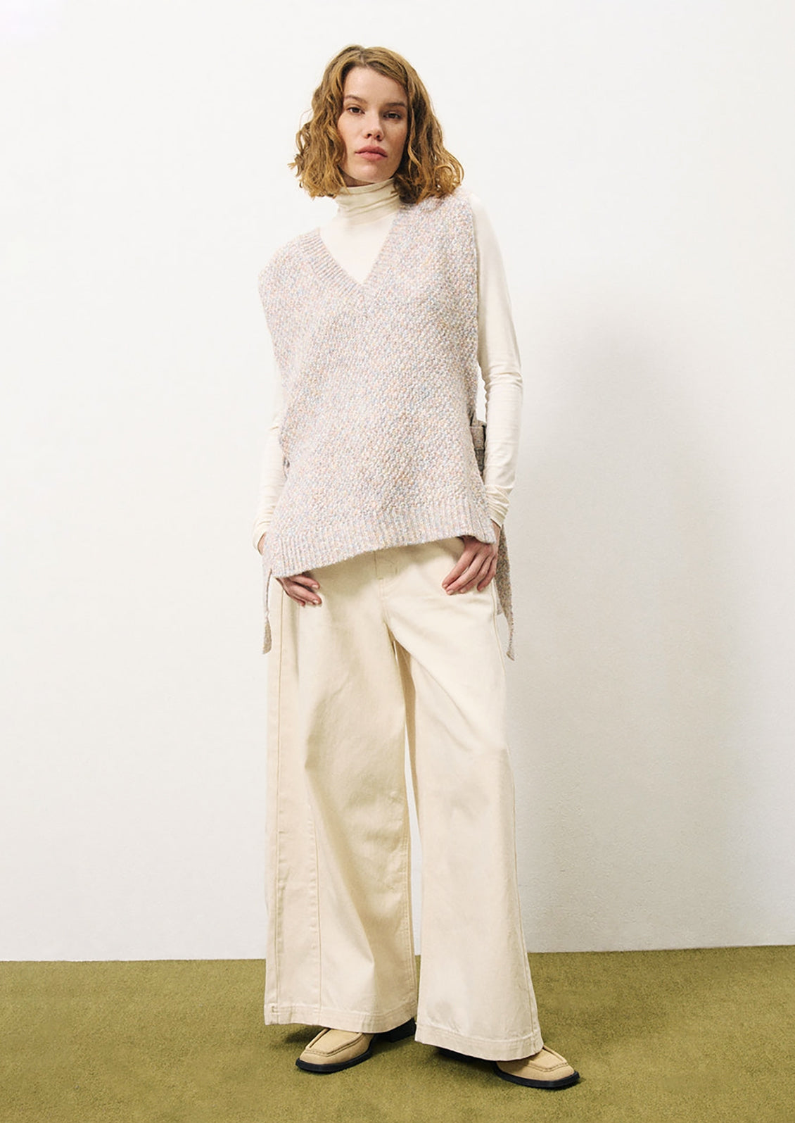 A woman wearing a long tunic style sweater vest in pastel yarn.