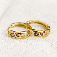 1: A pair of gold huggie hoops with embedded crystals in a mix of colors and shapes.