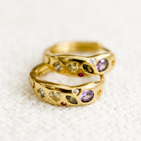 3: A pair of gold huggie hoops with embedded crystals in a mix of colors and shapes.