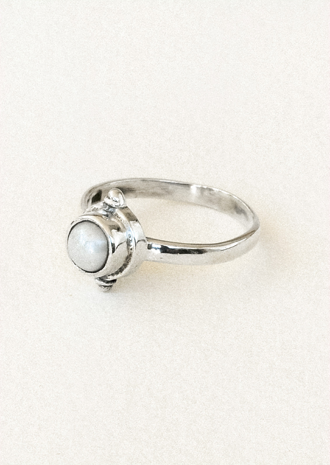 Side view of a sterling silver ring with a faux pearl in the center.