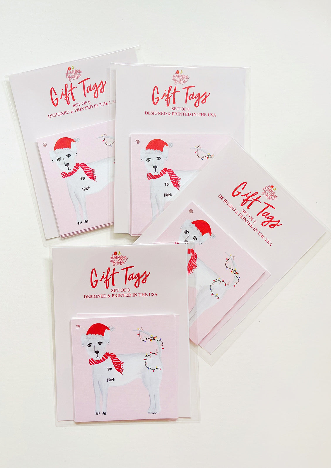 Pink square gift tags with image of white dog wearing Santa hat and tree lights.