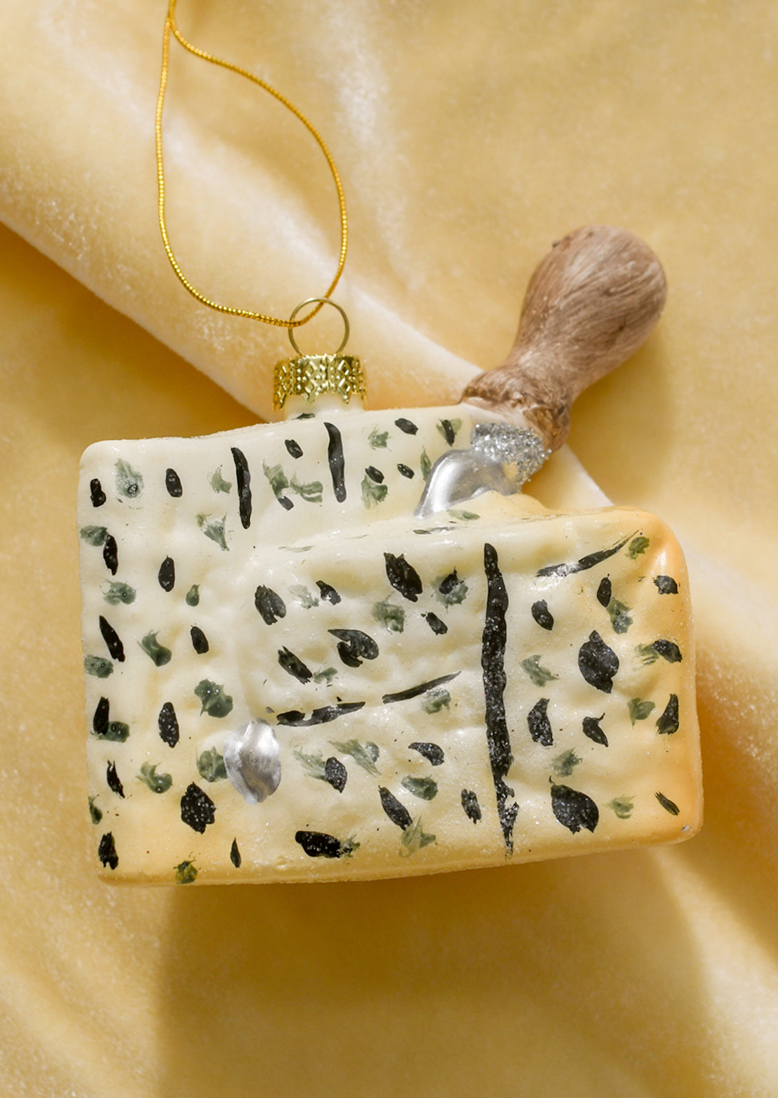 A glass ornament of a wedge of gorgonzola with cheese knife sticking out.