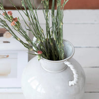 1: A white ceramic vase in situ with carnations.