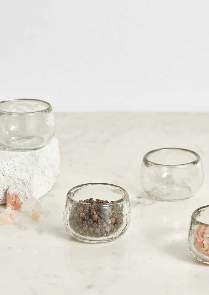 1: Small glass bowls holding salt and pepper.