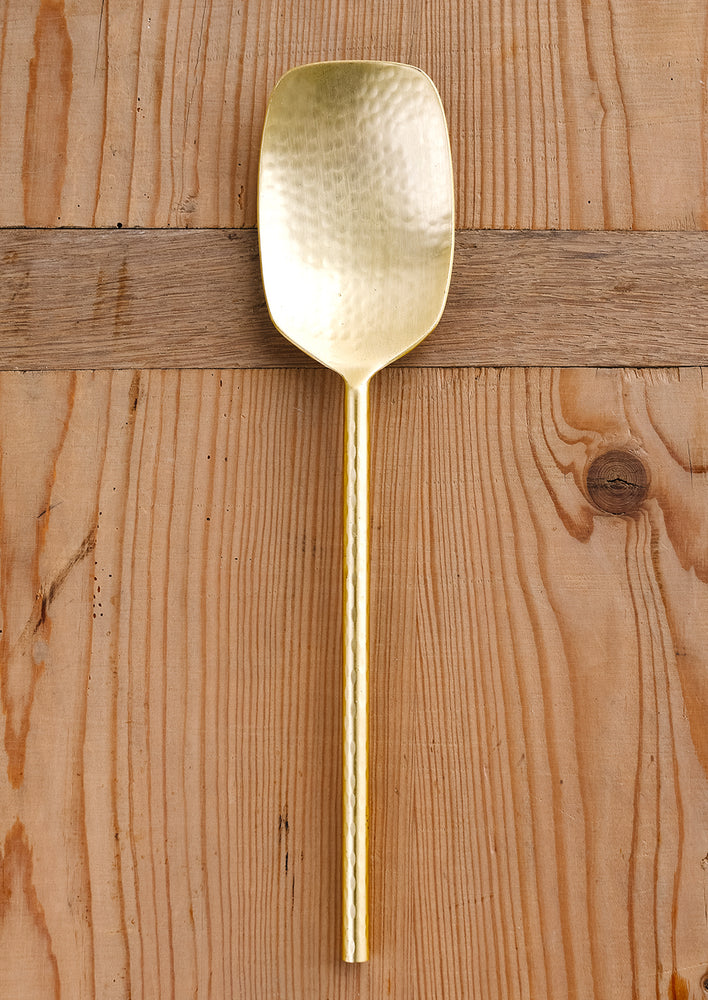 1: A gold serving spoon with modern, minimal shape.