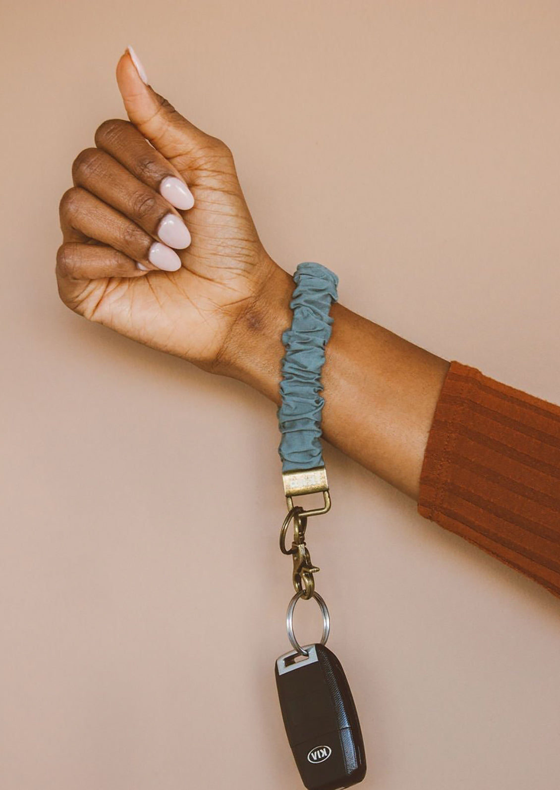 A harbor blue scrunchie wristlet keychain around a woman's wrist.