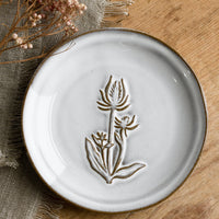 Thistle: A grey glazed brown clay mini plate with raised flower design.