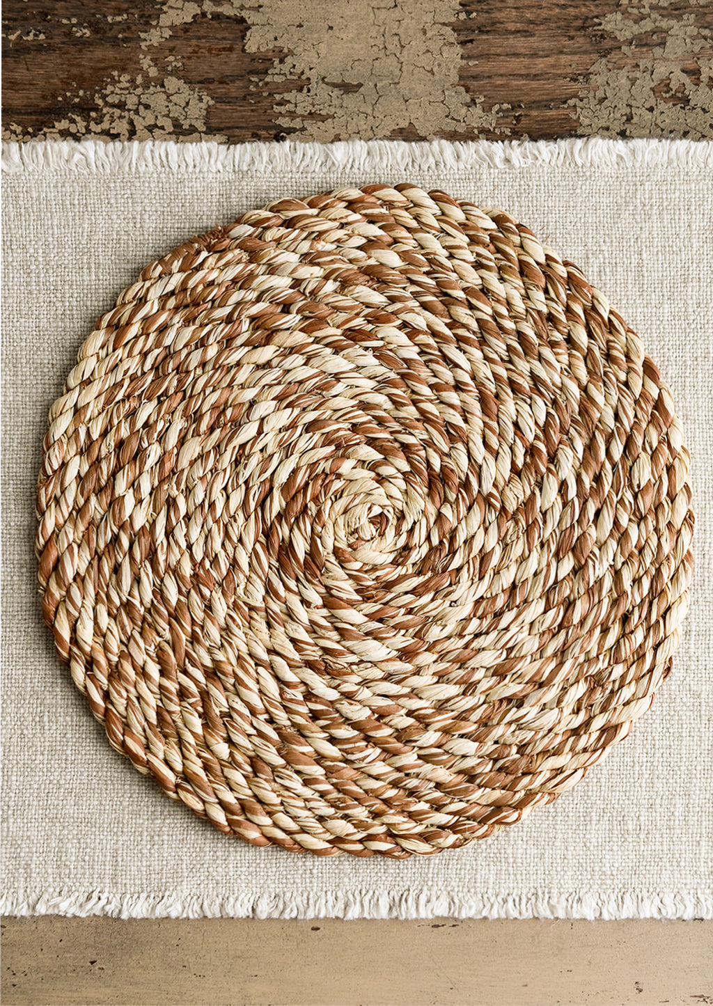 Sunbaked Brown: A round woven raffia placemat in natural and brown.