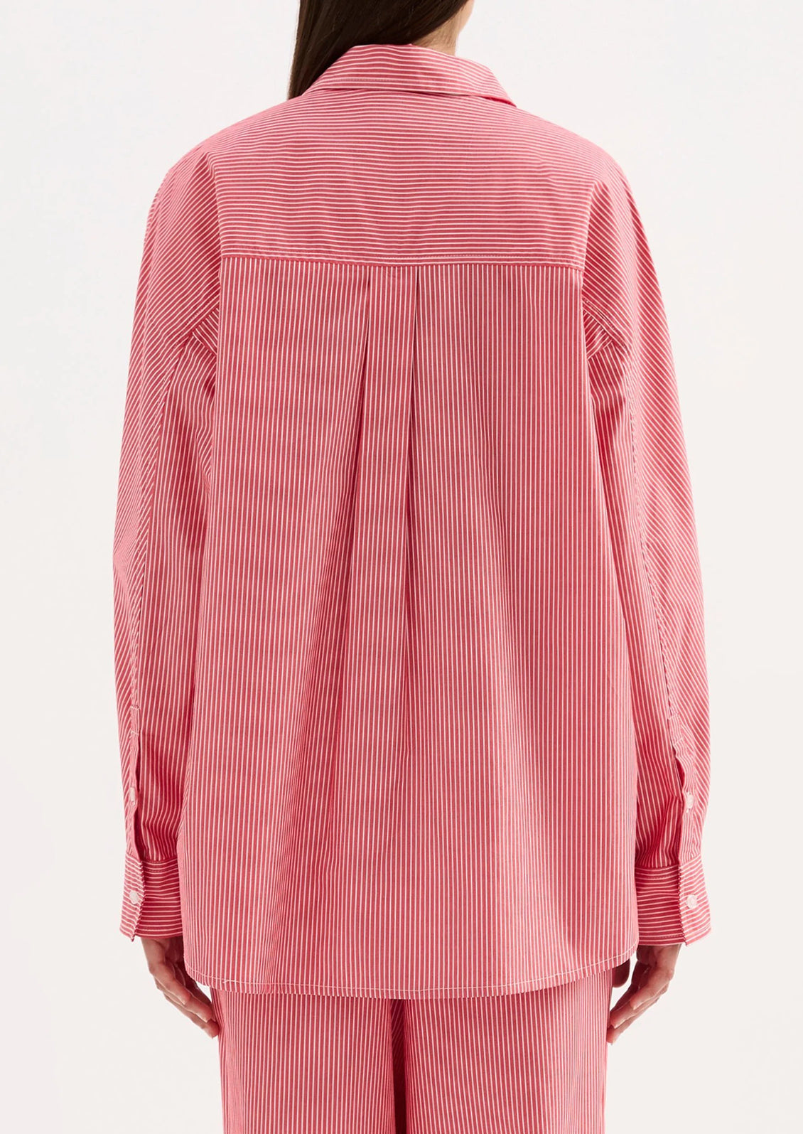 Pink striped shirt worn by a person on a white background