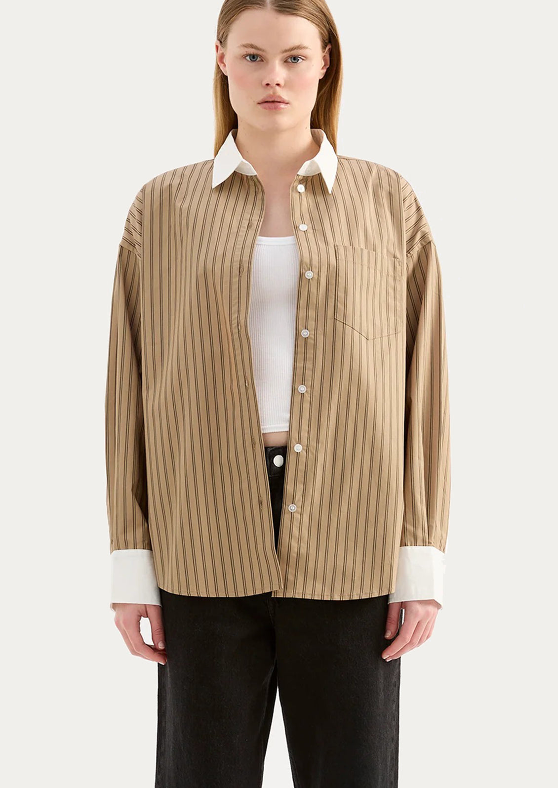 A woman wearing a beige striped shirt with white collar and cuffs.