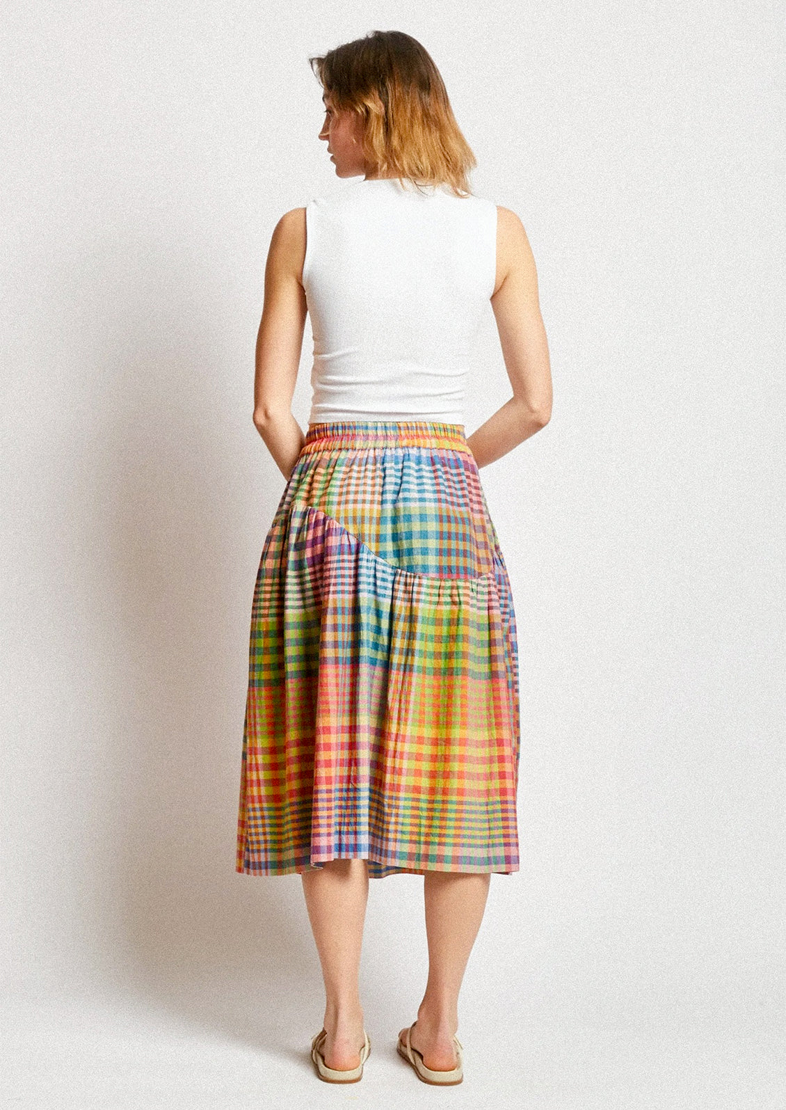 A person wearing a cotton skirt in colorful plaid.